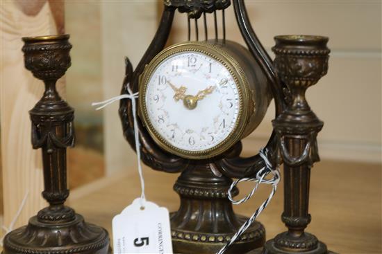 An early 20th century French patinated bronze garniture, clock 21.5cm. candlesticks 15cm.